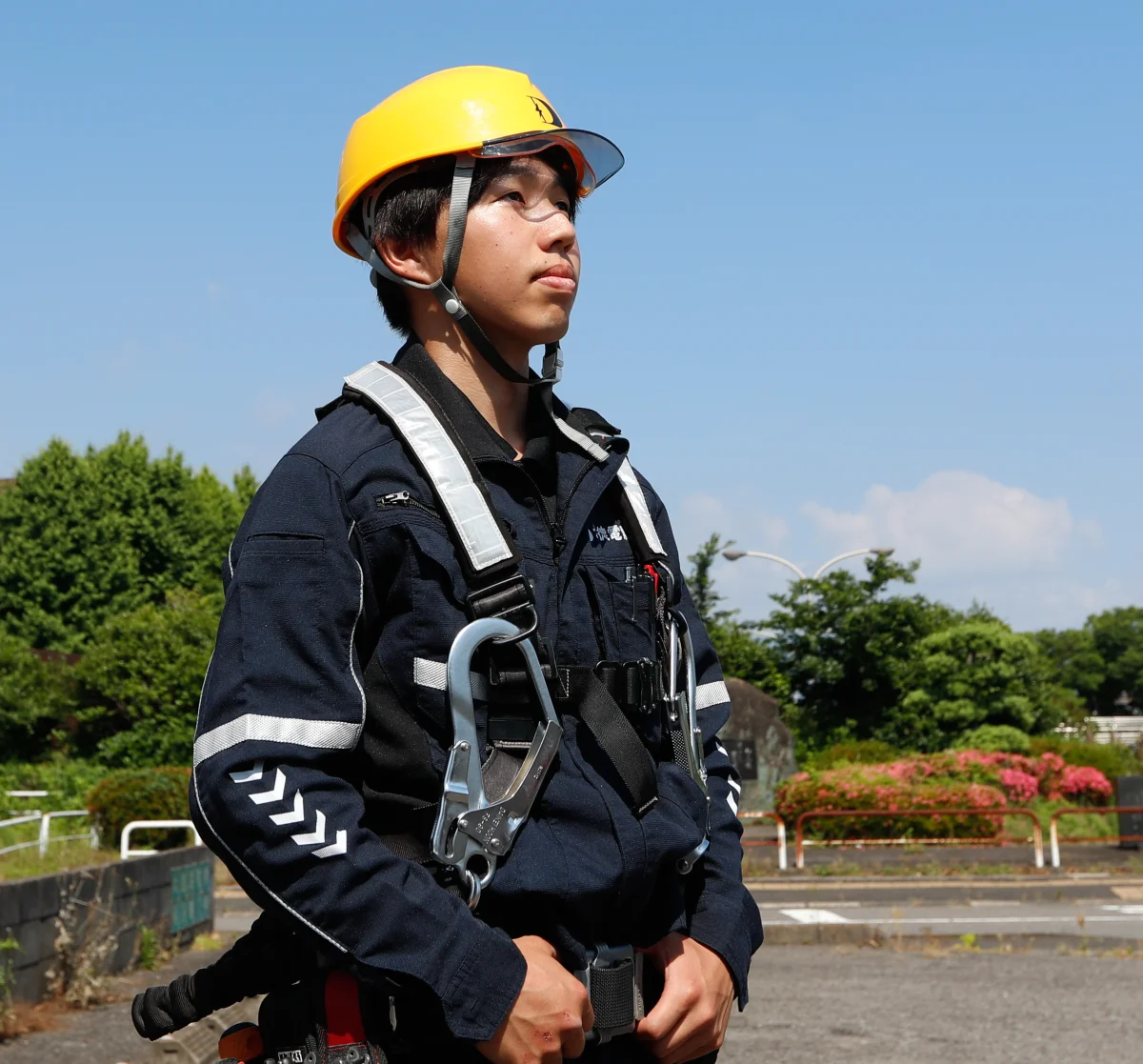 ヘルメットとハーネスを着けて現場に立つ嶋田さん