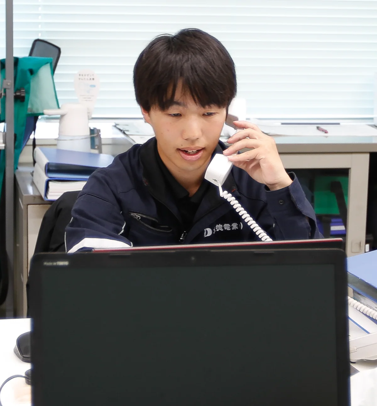 退勤前にデスクで電話対応する嶋田さん